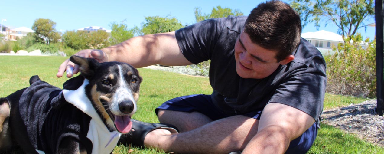 Young man patting Loki the Therapy Dog