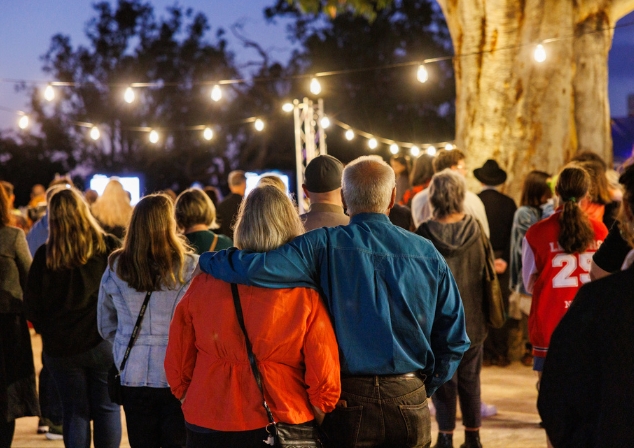Crowd at an event with festoon lights in the background.