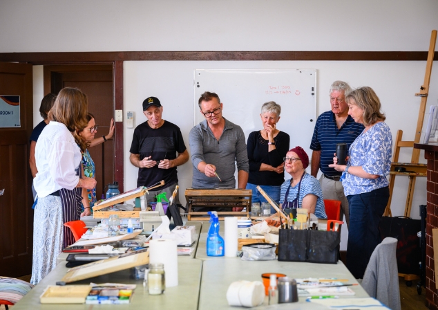 Man wearing glasses teaching an art class.