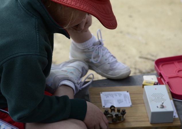 Primary school-aged student sitting and looking down inspecting a piece of old wireless technology.