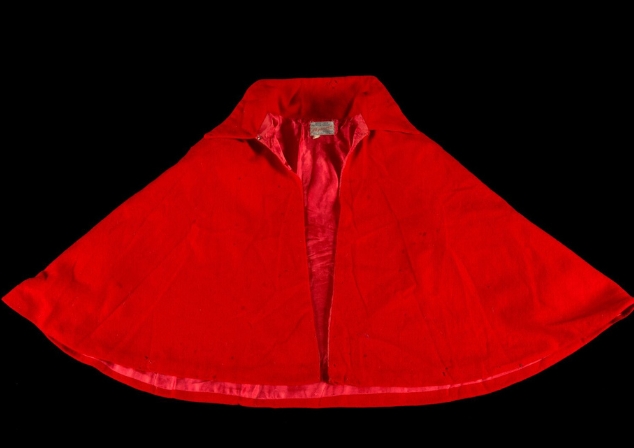 A red nurses cape from the 1960s laid out on a black background.