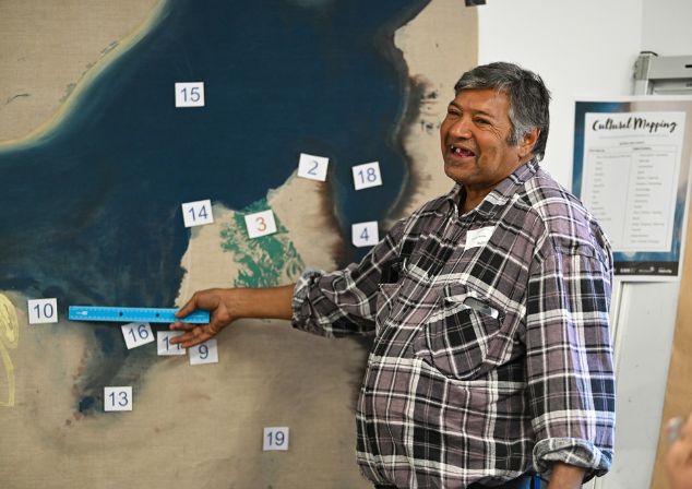 A man using a ruler to point at a colourful linen map with numbers marking places in the City of Melville.