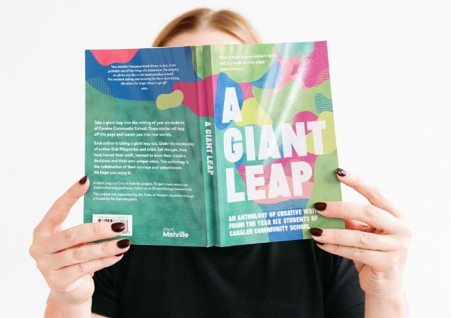 Person with face hidden behind book, reading Write Club book 'A Giant Leap'.