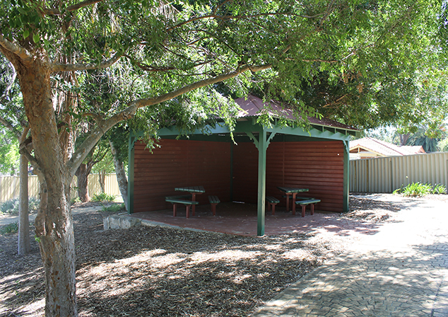 Photo of seating area under a gazebo. Tree in foreground.