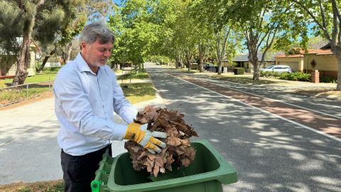 An image of a man putting leaves into the FOGO bin