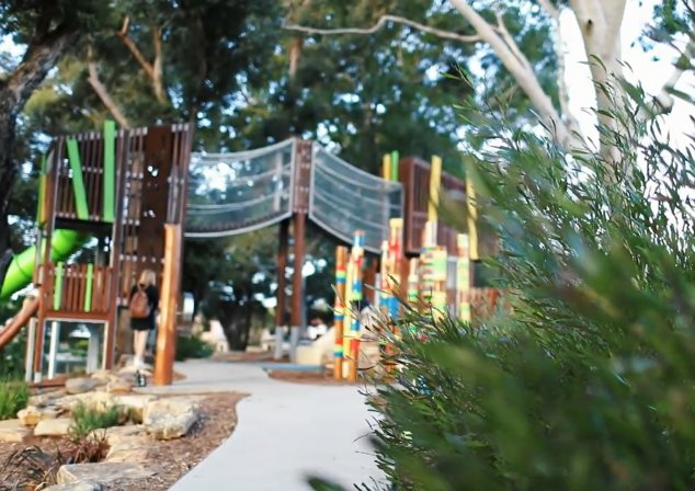 Photo of playground, bush in foreground