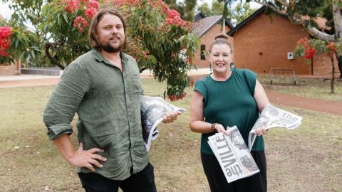 Image of a man and a women giving out copies of the Ville