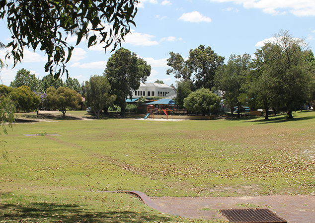 Large grassed area with children's playground and building