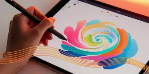 A hard holds a stylus, drawing a colourful flower on a tablet screen.