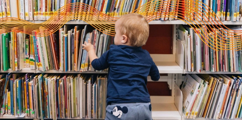 Rhymetime event. Toddler in a library looking at books.