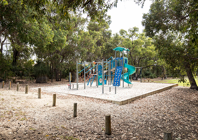 Children's playground in sand pit with tall trees surrounding