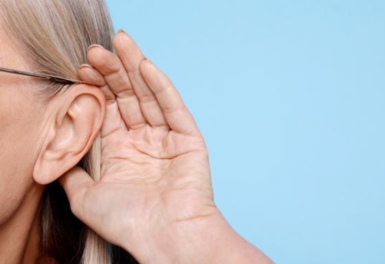 Woman placing hand by ear, doing a hearing test.