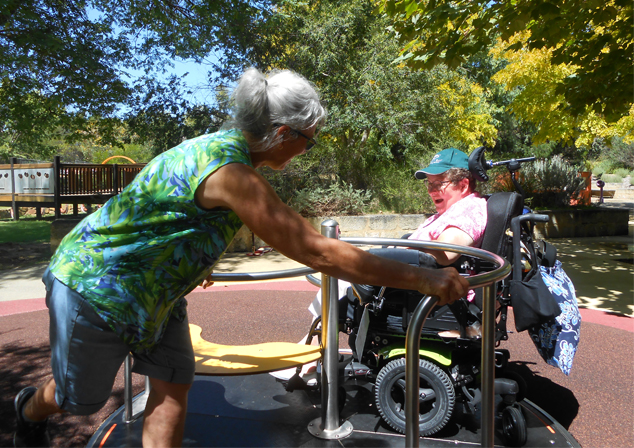 community member using wheelchair accessible merry go round