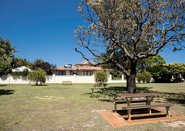Children's playground with picnic bench, grassed area and tall trees