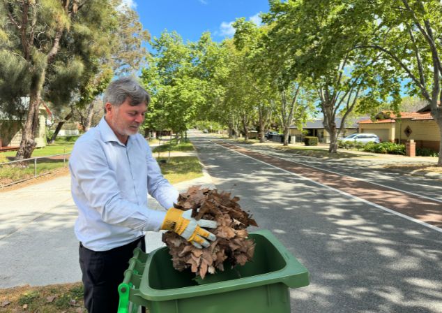 A man placing leaves into FOGO bin