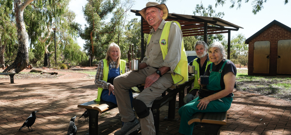 Four volunteers sitting at a park bench.