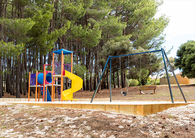 Children's playground in sand pit with tall trees surrounding