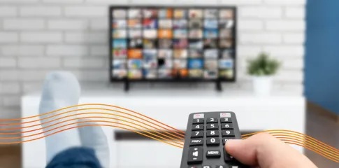 A remote is pointing at a television screen, which displays a streaming platform.