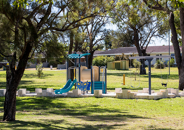 Children's playground in sand pit with tall trees surrounding