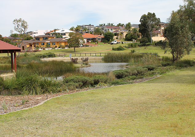 grassed bank looking onto a lake and a gazebo